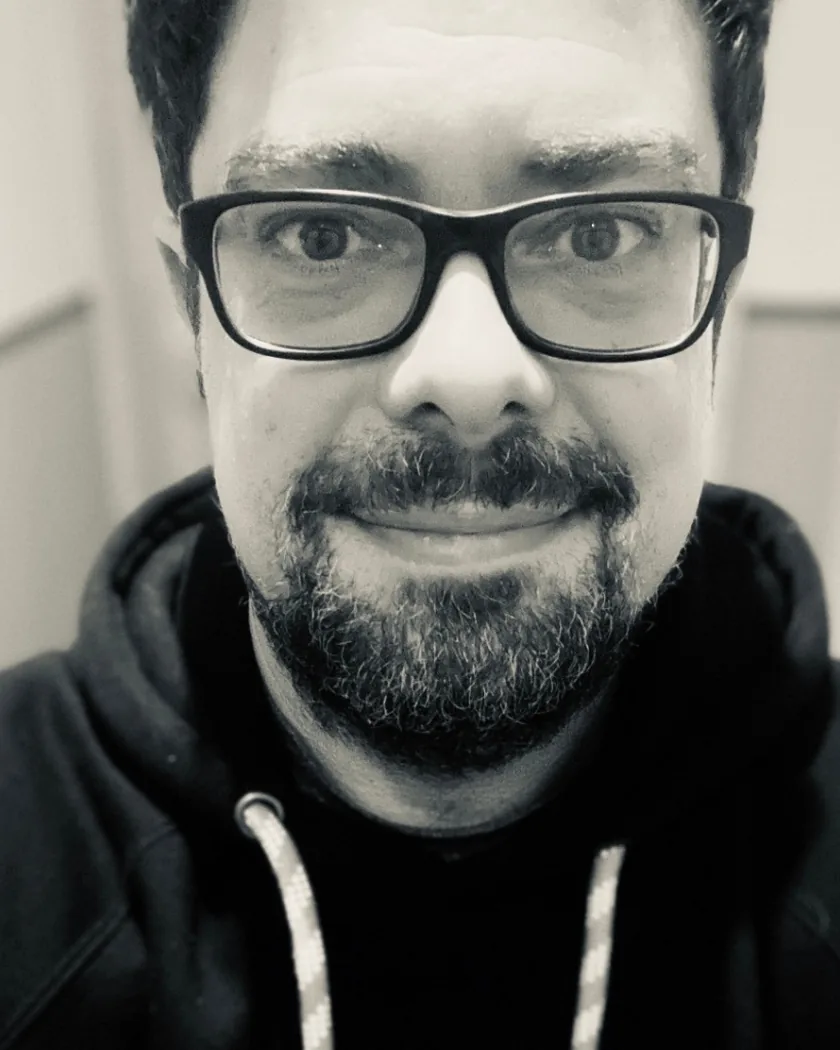 Stefan Bodeit, Schwarzweissaufnahme, Brille mit kräftigem Rahmen, Vollbart, dunkler Kapuzenpullover, blickt direkt in die Kamera.